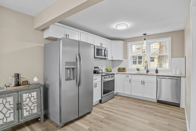 kitchen featuring decorative light fixtures, white cabinetry, sink, and appliances with stainless steel finishes