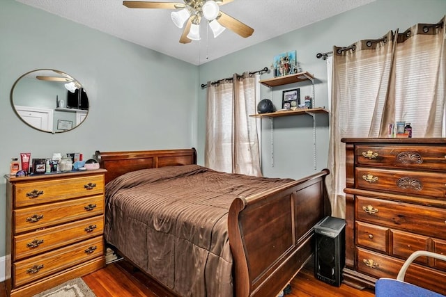 bedroom with a textured ceiling, dark wood-style flooring, and ceiling fan