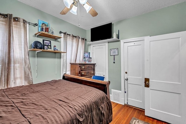 bedroom featuring visible vents, a textured ceiling, wood finished floors, and a ceiling fan