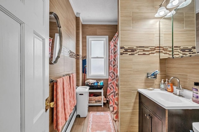 full bathroom featuring tile walls, vanity, ornamental molding, wood finished floors, and a textured ceiling