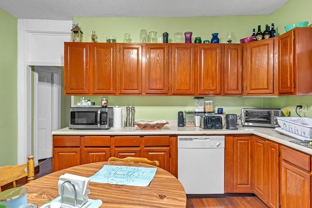 kitchen featuring stainless steel microwave, light countertops, white dishwasher, and a toaster