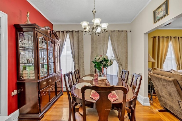 dining room featuring baseboards, light wood finished floors, an inviting chandelier, a baseboard heating unit, and crown molding