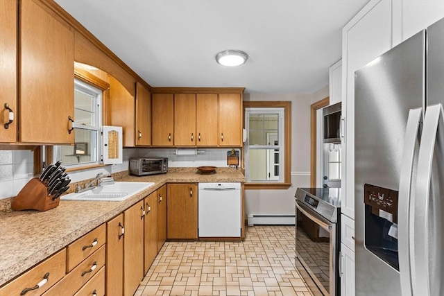 kitchen with a sink, a toaster, light countertops, stainless steel appliances, and a baseboard radiator