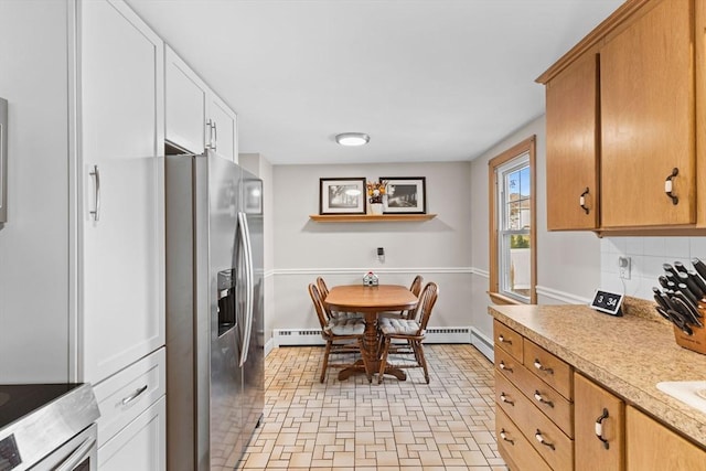 kitchen with white cabinets, stainless steel fridge with ice dispenser, light countertops, decorative backsplash, and baseboards