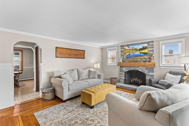 living room featuring a wealth of natural light, arched walkways, baseboard heating, and wood finished floors