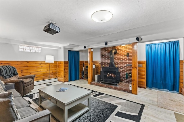 living area featuring a wainscoted wall, wooden walls, a wood stove, and a baseboard radiator