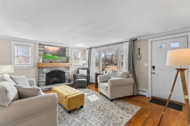 living area with plenty of natural light, a fireplace, wood finished floors, and a baseboard radiator