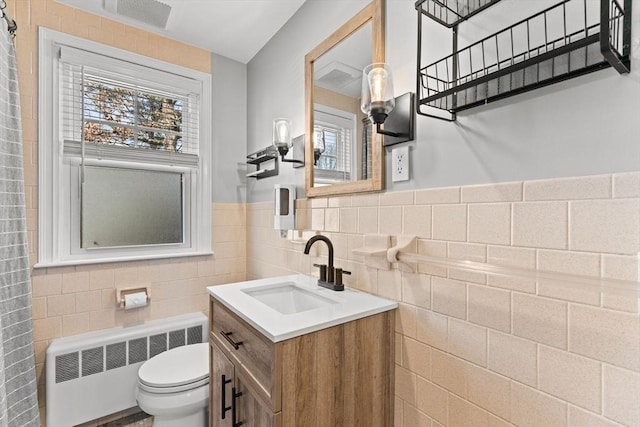 bathroom featuring visible vents, radiator, toilet, vanity, and tile walls