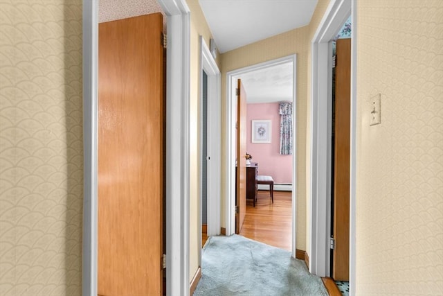 corridor with baseboard heating and carpet floors