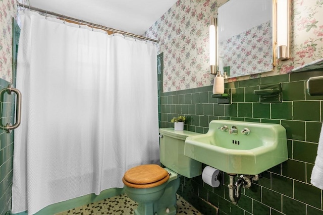 full bathroom with shower / tub combo, tile patterned flooring, toilet, tile walls, and sink