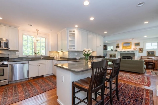 6 Willow St, Wellesley, MA 02481 - kitchen with appliances with stainless steel finishes, a peninsula, white cabinets, a kitchen bar, and glass insert cabinets