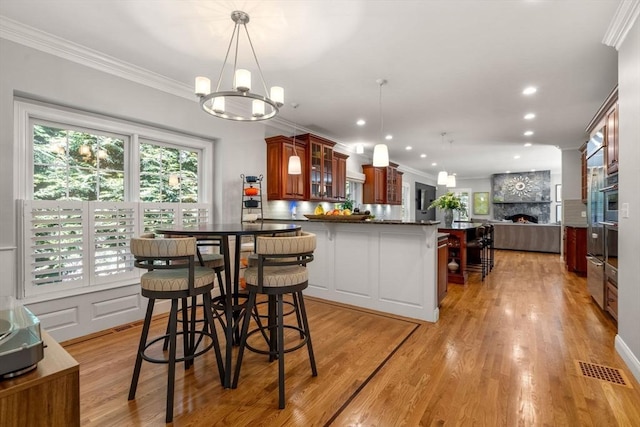 127 Shade St, Lexington, MA 02421 - dining space with ornamental molding, a fireplace, light wood-style flooring, recessed lighting, and a chandelier