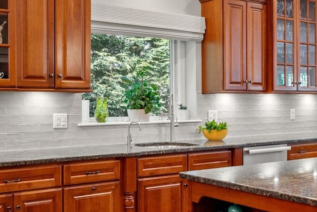 127 Shade St, Lexington, MA 02421 - kitchen featuring glass insert cabinets, dark stone counters, decorative backsplash, and brown cabinets