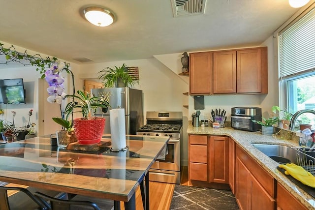 18 Emerald Ave, Webster, MA 01570 - kitchen with appliances with stainless steel finishes, brown cabinets, light stone countertops, and granite tiled floors
