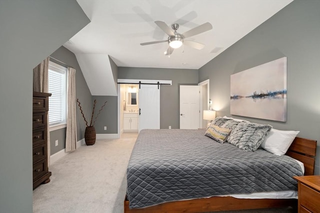 carpeted bedroom featuring connected bathroom, a barn door, and ceiling fan