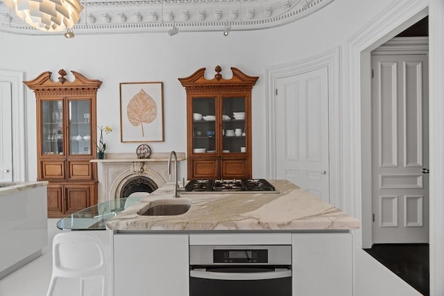 kitchen with light stone counters, a sink, and stainless steel gas stovetop