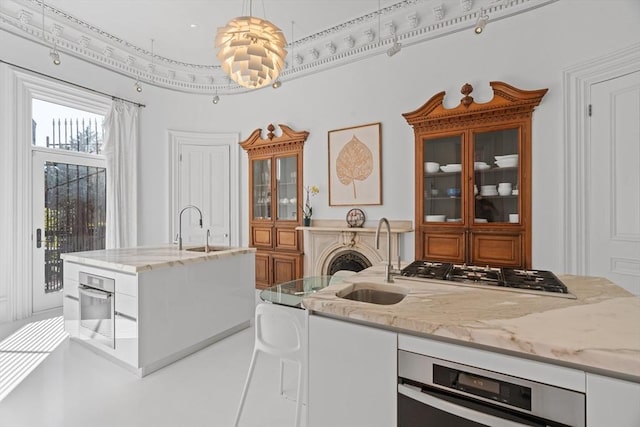 kitchen with a sink, a center island with sink, light stone countertops, and stainless steel appliances