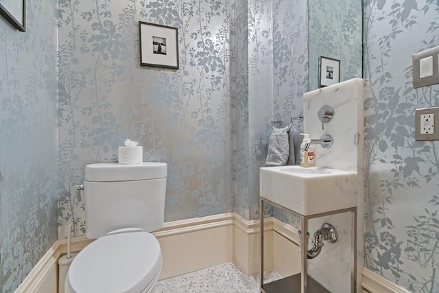 half bathroom featuring toilet and wallpapered walls