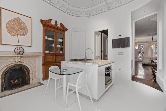 kitchen with a sink, a center island with sink, a kitchen breakfast bar, and stainless steel oven