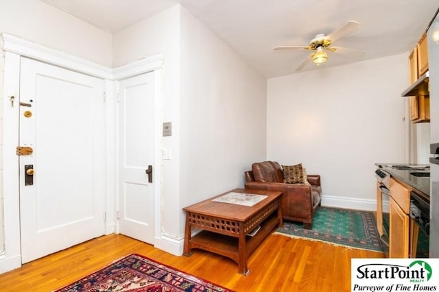 sitting room with light wood-style floors, baseboards, and a ceiling fan