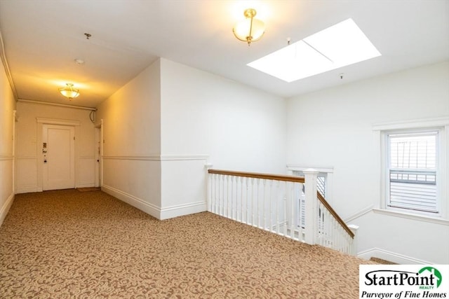 corridor featuring carpet, baseboards, an upstairs landing, and a skylight