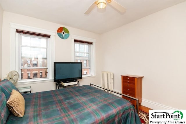 bedroom with radiator heating unit, baseboards, ceiling fan, and wood finished floors