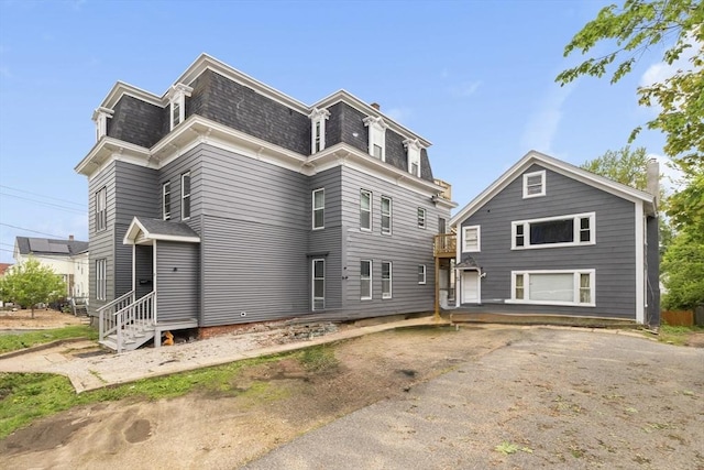 view of front of home featuring mansard roof and a shingled roof