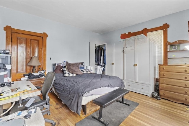 bedroom featuring light wood-style flooring, an office area, and a closet