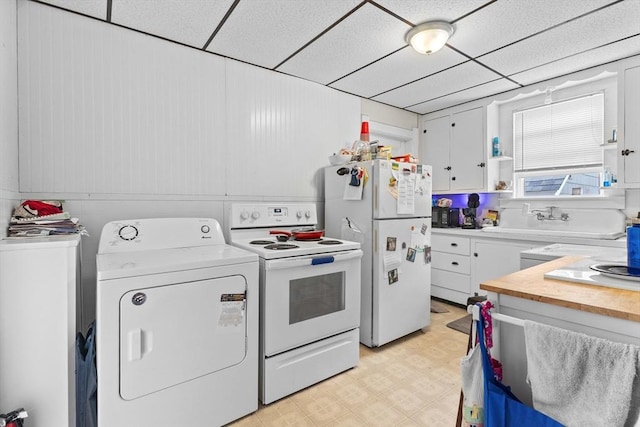 kitchen with white appliances, light floors, white cabinetry, a paneled ceiling, and a sink