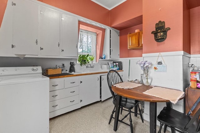 kitchen featuring washer / dryer, white cabinetry, a sink, and light countertops