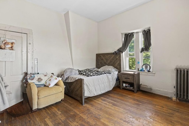 bedroom featuring radiator heating unit, hardwood / wood-style flooring, and baseboards