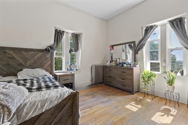 bedroom featuring radiator and hardwood / wood-style flooring