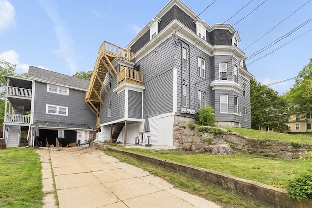 view of front of house featuring a balcony, mansard roof, and a front lawn