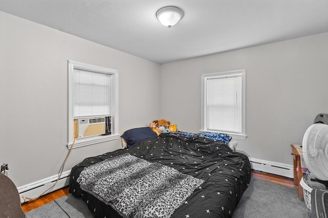 bedroom featuring baseboard heating, wood finished floors, and cooling unit