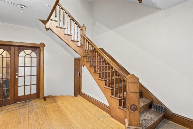stairway with wood-type flooring and french doors