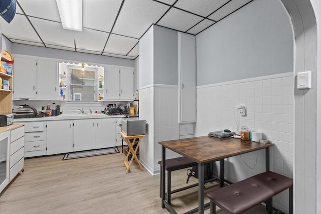 kitchen featuring open shelves, a paneled ceiling, white cabinetry, light wood finished floors, and light countertops