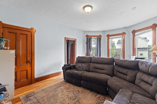living room with light wood finished floors, baseboards, and a textured ceiling