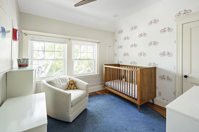 49 Prince St Unit 2, Boston, MA 02130 - bedroom with a crib, wood finished floors, baseboards, ceiling fan, and wallpapered walls