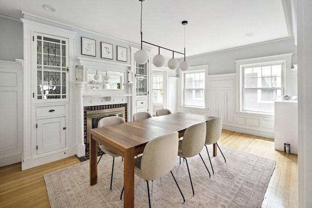 49 Prince St Unit 2, Boston, MA 02130 - dining room with a glass covered fireplace, light wood-type flooring, crown molding, a decorative wall, and wainscoting