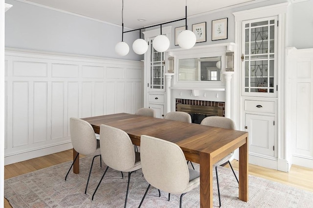 49 Prince St Unit 2, Boston, MA 02130 - dining space featuring light wood-style floors, crown molding, a fireplace, a decorative wall, and a wainscoted wall