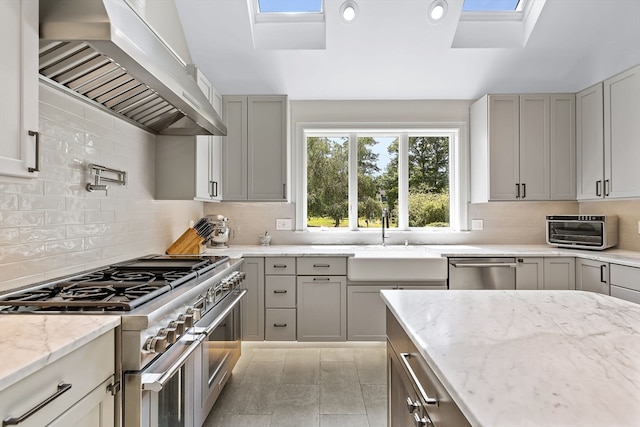 kitchen with appliances with stainless steel finishes, tasteful backsplash, and wall chimney exhaust hood