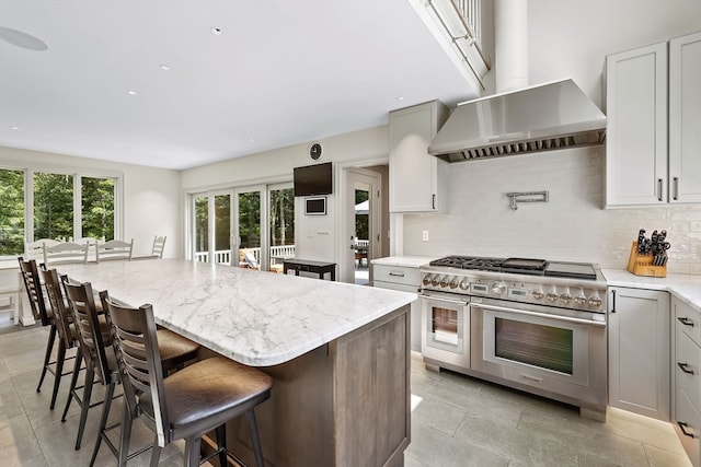 kitchen with a breakfast bar, light tile patterned flooring, double oven range, a center island, and decorative backsplash