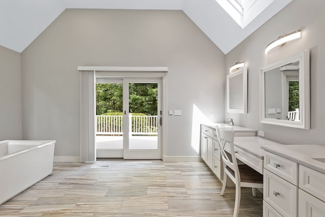 bathroom with high vaulted ceiling, a skylight, vanity, and a wealth of natural light