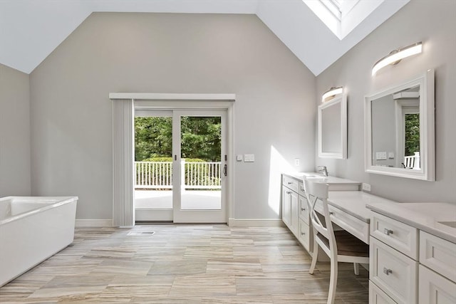 bathroom featuring vanity, a bath, and vaulted ceiling with skylight