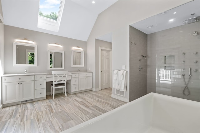 bathroom with vaulted ceiling with skylight, dual bowl vanity, a tile shower, and hardwood / wood-style floors