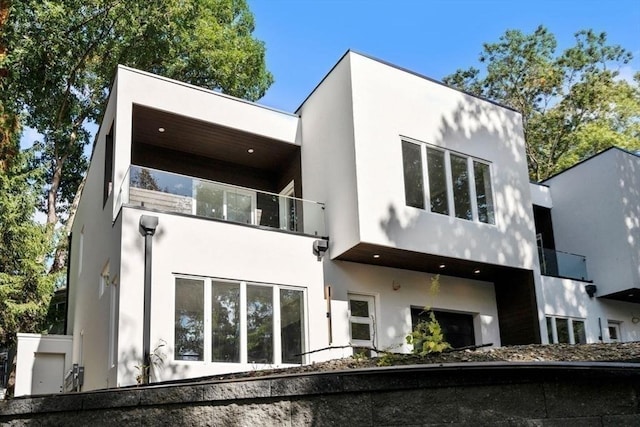 back of house with a balcony and stucco siding