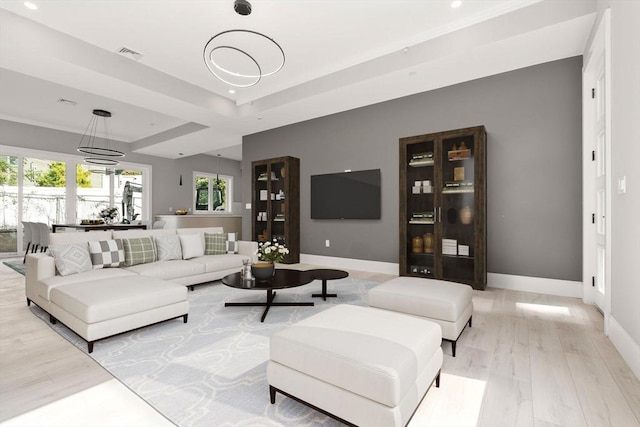 living room with light wood-style flooring, recessed lighting, visible vents, baseboards, and a tray ceiling