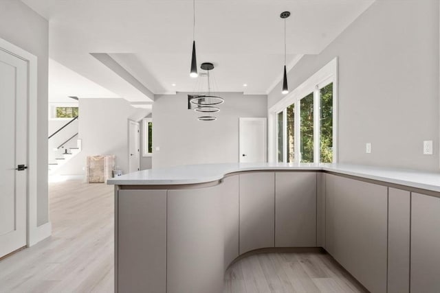 kitchen with a wealth of natural light, pendant lighting, light countertops, and light wood finished floors