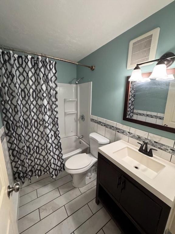 bathroom with toilet, vanity, tile walls, wainscoting, and shower / bath combo