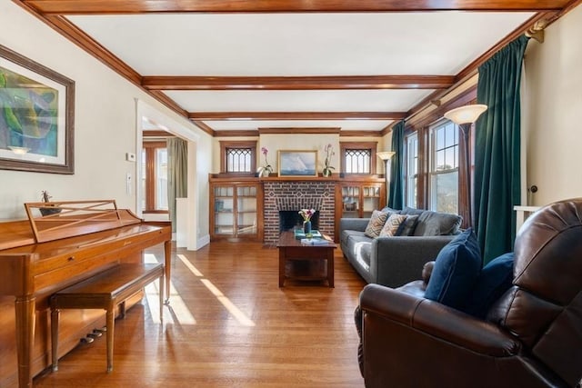 living room with hardwood / wood-style flooring, ornamental molding, a brick fireplace, and beam ceiling